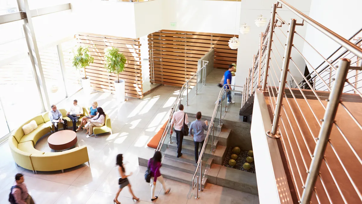 Employees walk and congregate in the entrance to an office building.