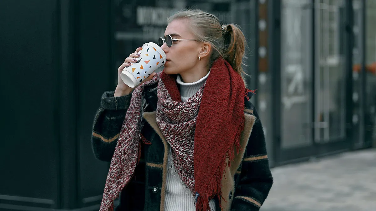 Person walking down street drinking hot drink