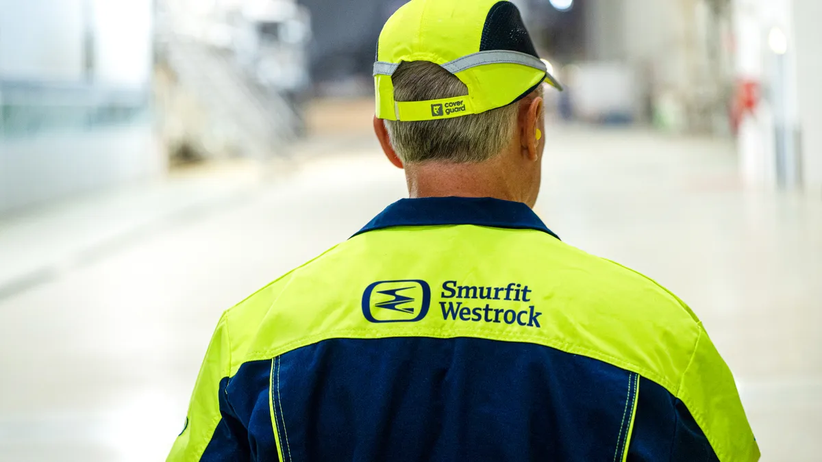 Rear view of a person in a Smurfit WestRock jacket and a Cover Guard hat