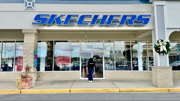 A Skechers storefront in an outdoor mall. A shopper walks into the door.