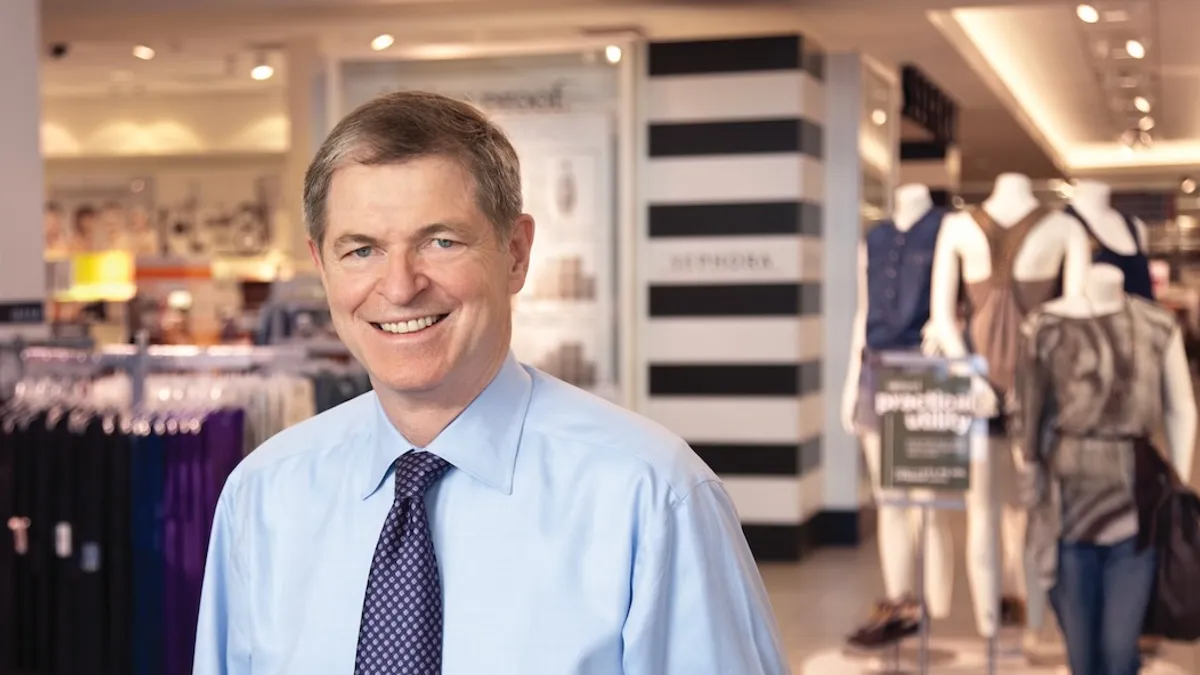 A person wearing a shirt and tie, smiling.