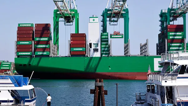 A man hoses down a boat near a container ship at the Port of Los Angeles.