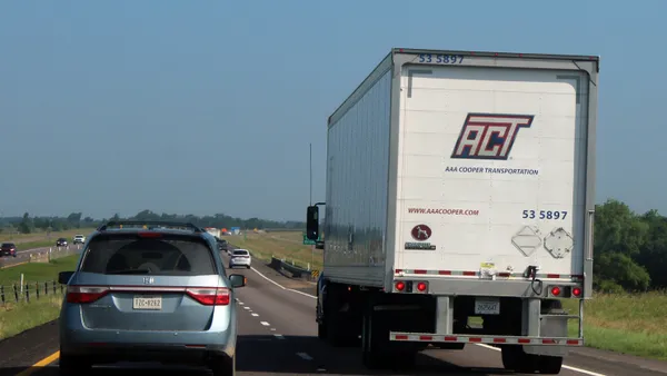 An ACT trucker drives on a Texas highway next to passenger vehicles in May 2024 under a clear blue sky.