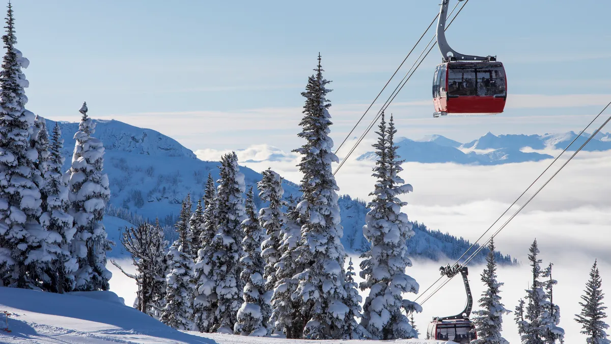 A red gondola ascends a snow-covered mountain.