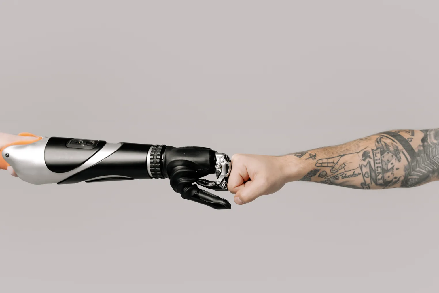 A prosthetic arm and a tattooed arm fist-bump