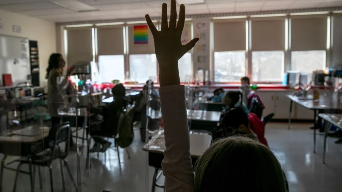 child raising her hand in a classroom