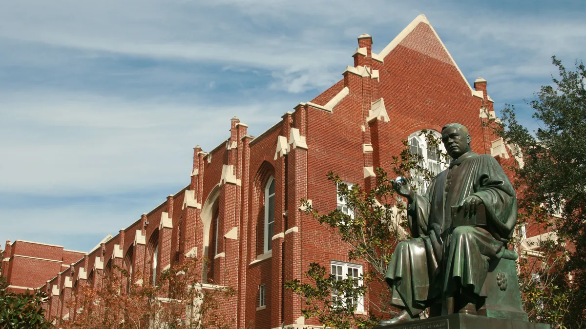 An old statue stands in front of an academic building