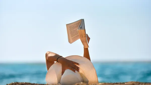 Shot of woman reading in a chair on the beach