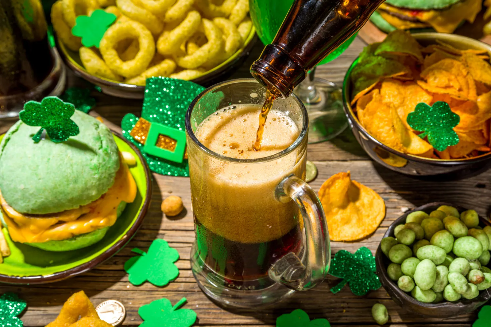 A close up image of a bottle being poured into a mug alongside various green-centric menu items for St. Patrick's Day