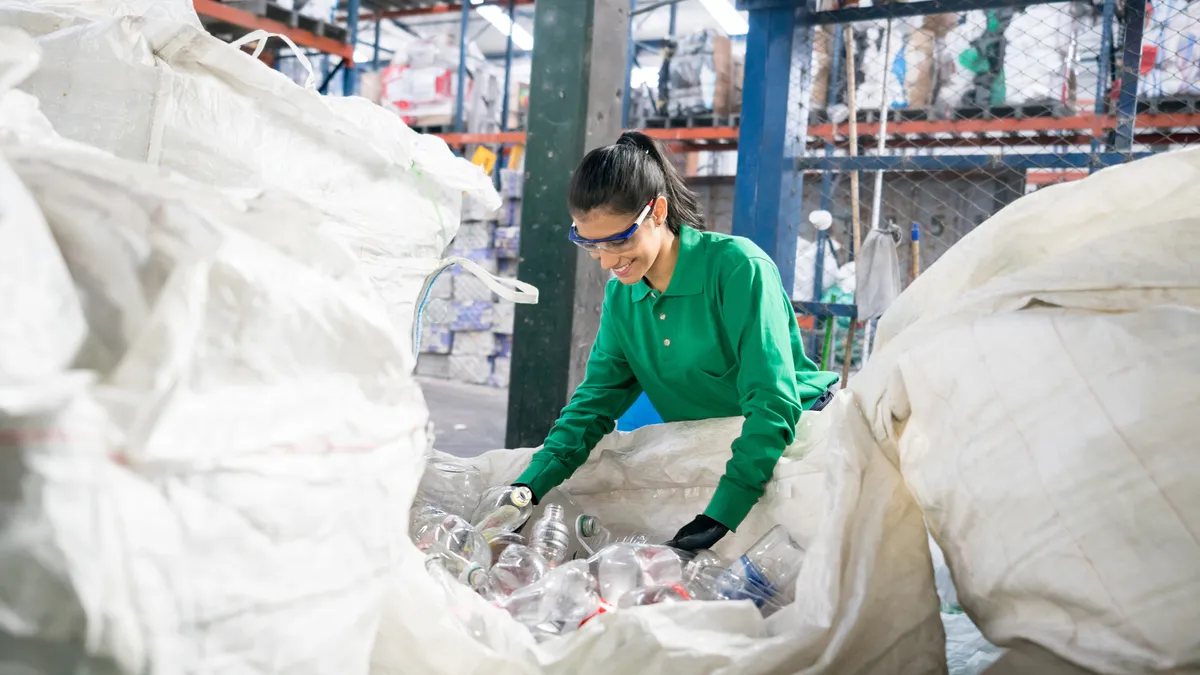 Woman working in a recycling factory sorting some bottles and looking very happy