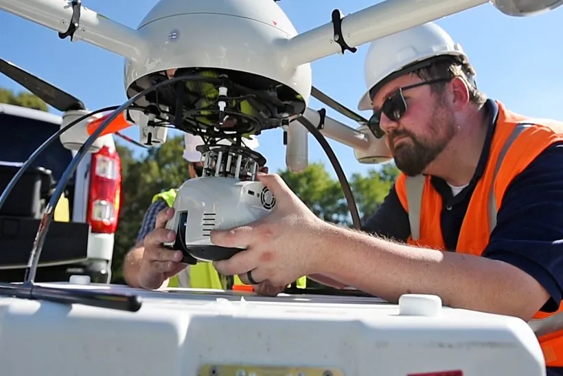 A person in a hard hat and safety vest works on a drone at the Paducah Site landfill in Kentucky