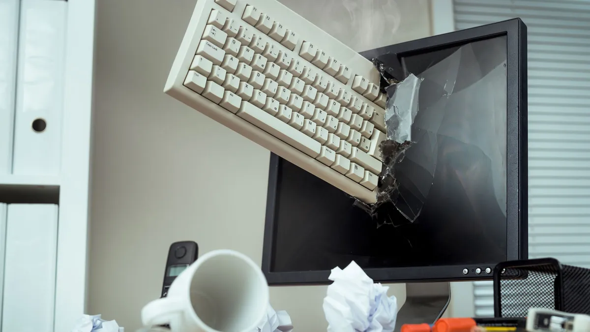 A keyboard smashed into a computer monitor