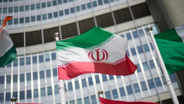 An Iranian flag flutters in front of a building with many windows