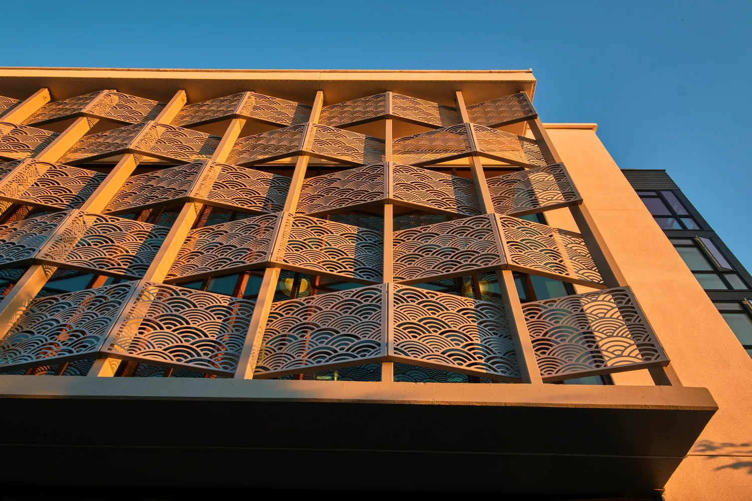 An undulating metal screen with a pattern of interlocking fans cut into the surface.