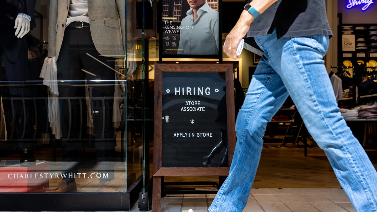 A person walks past a "hiring" sign.