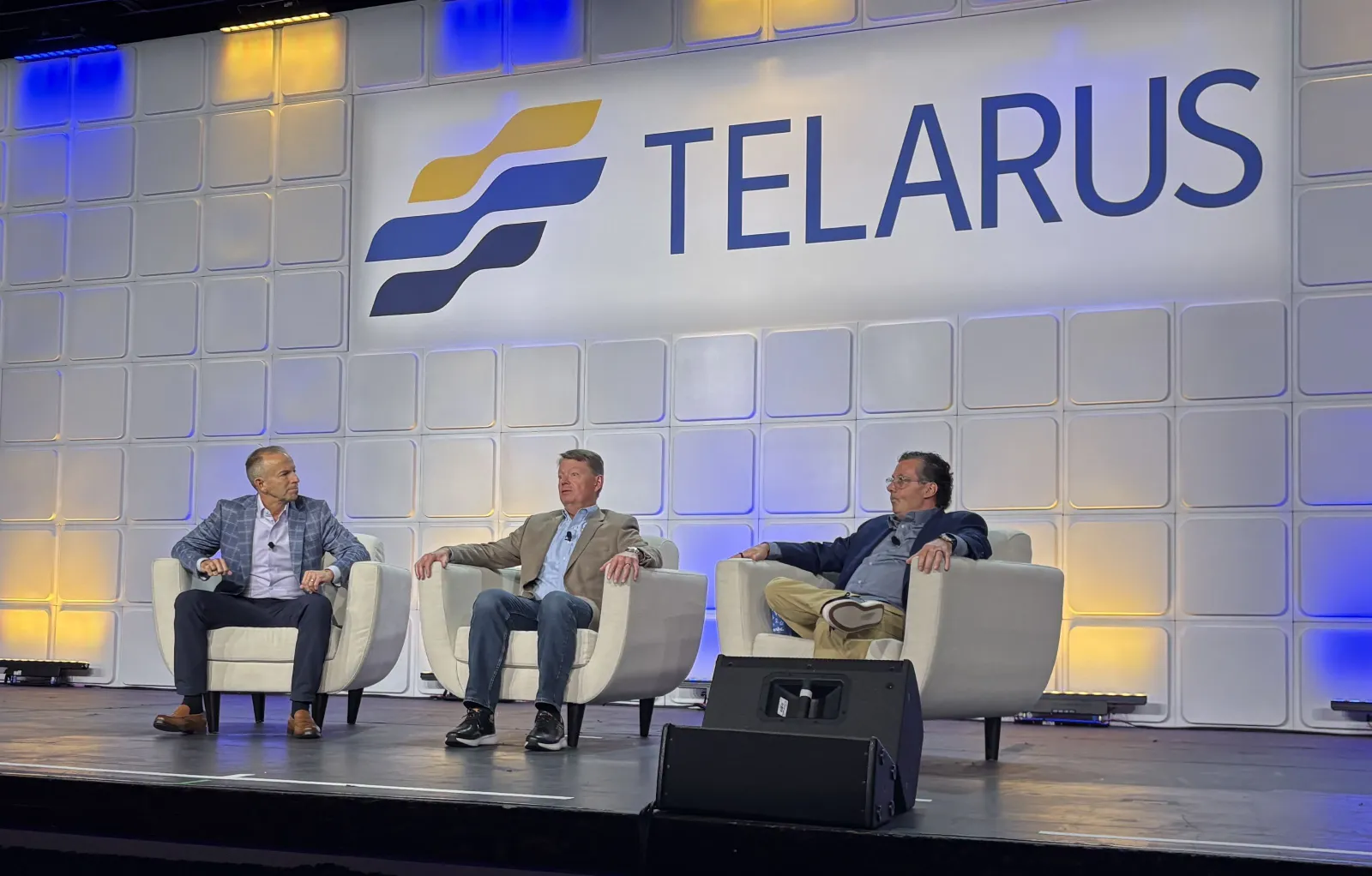 three men sit in a panel onstage