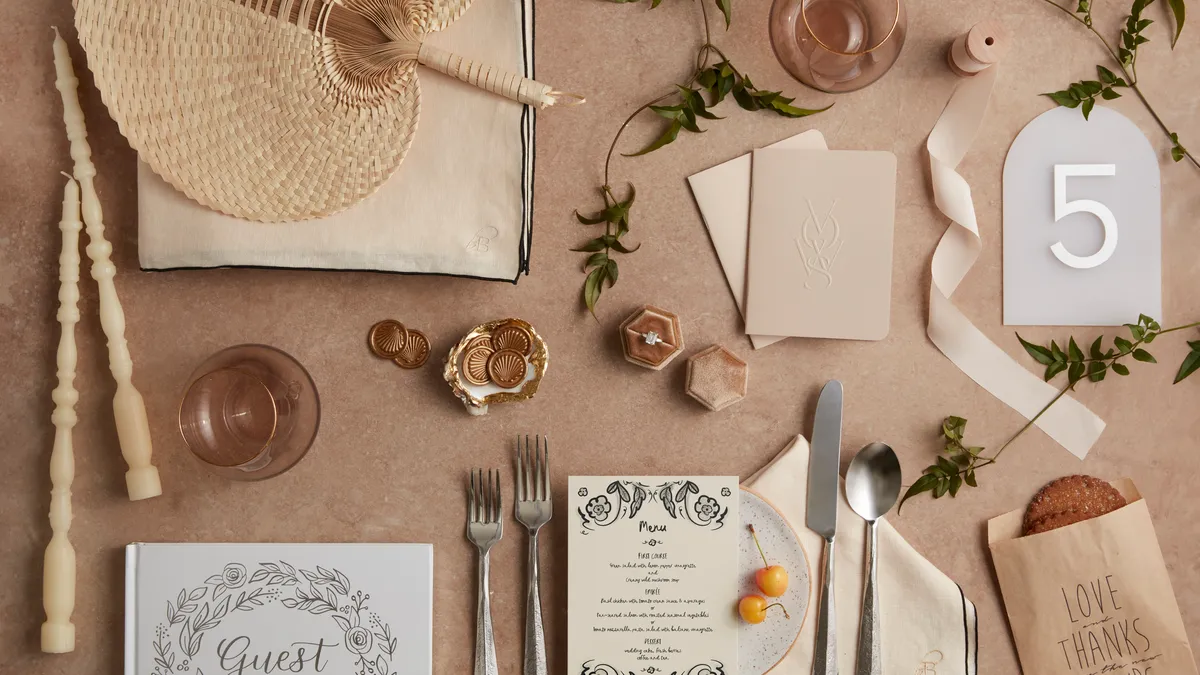 Tableau of wedding-related items including a place setting, guest book, candles, ribbon and fan.