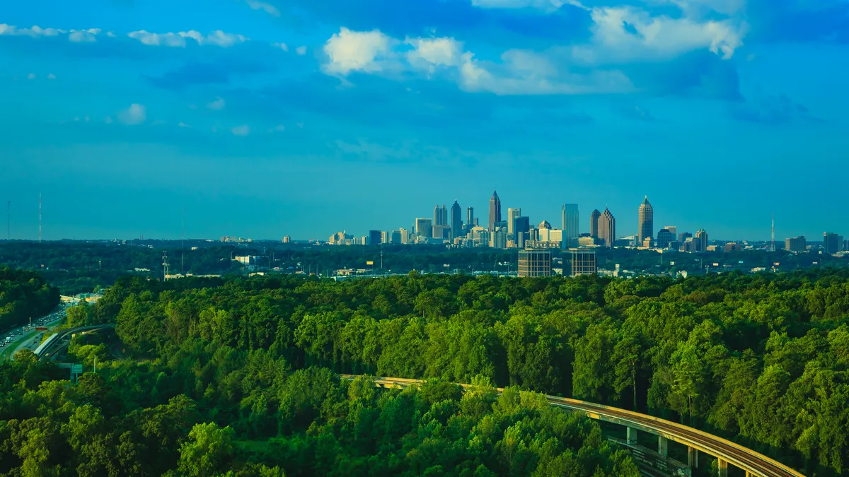 A wide angle view of Atlanta's skyline with trees in the foreground.