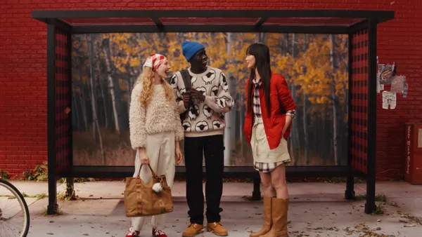 A group of people stand outside a bus stop in Woolrich x Target gear