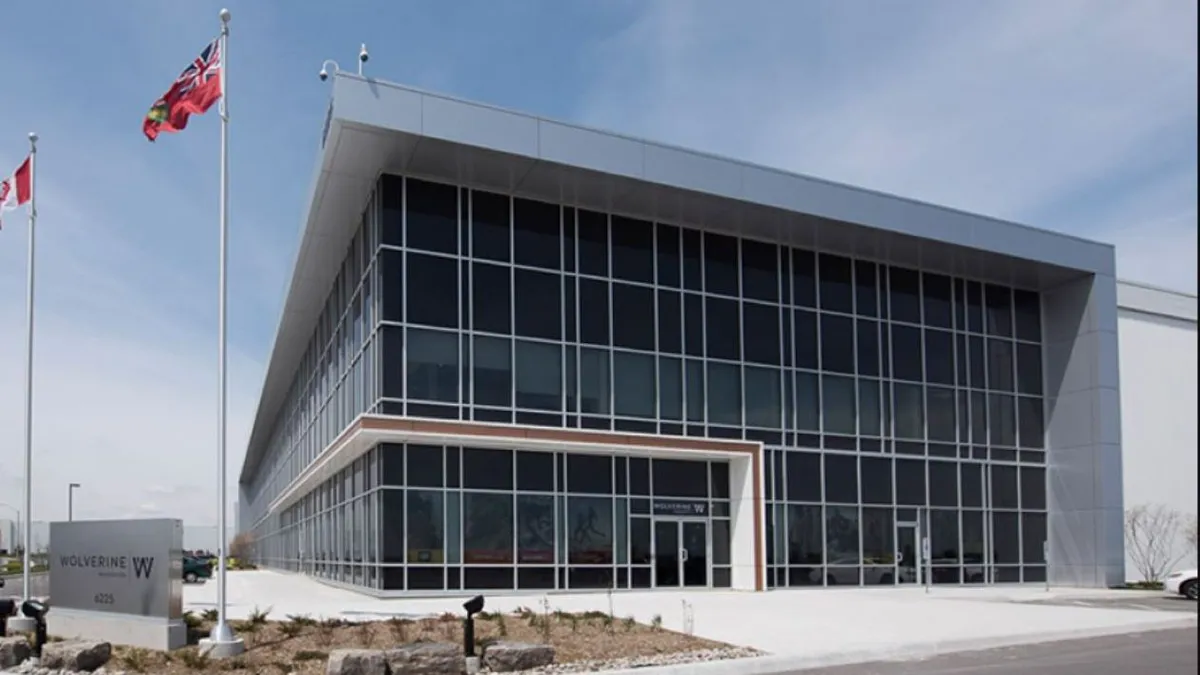 An exterior shot of the corner of a large corporate headquarters building with Canadian flags outside and the word "wolverine" on the front.