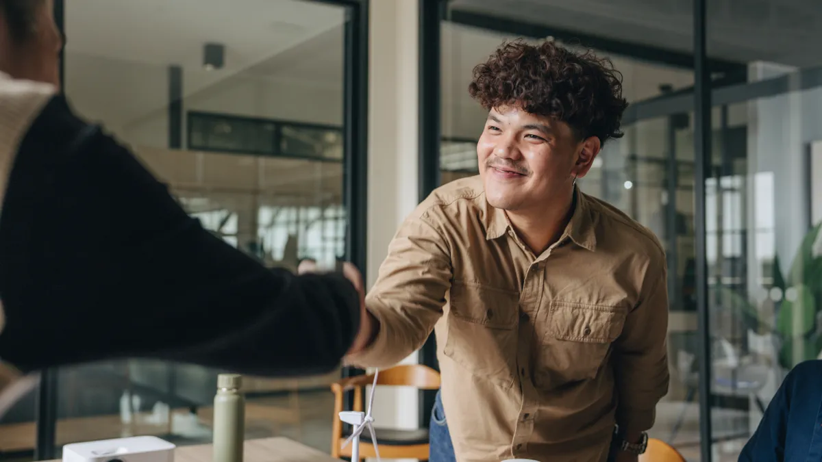 A man shakes a colleague's hand in an office setting