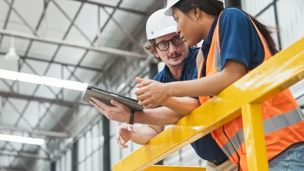 Two technicians look at a tablet in a facility.