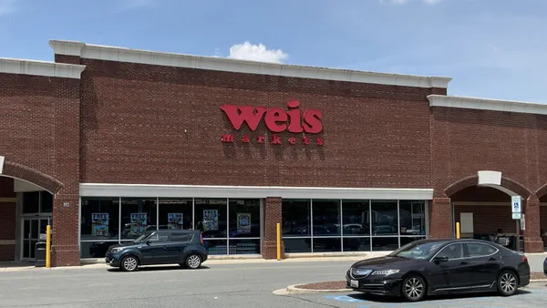Exterior of supermarket with a dark brick front and a red sign reading "Weis."