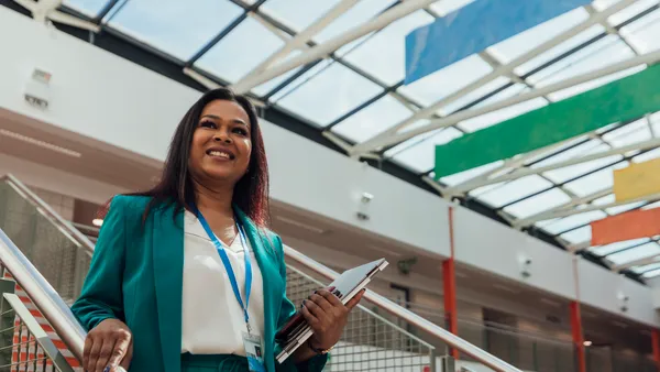 Female principal stood confidently on the stairs into the school hall.