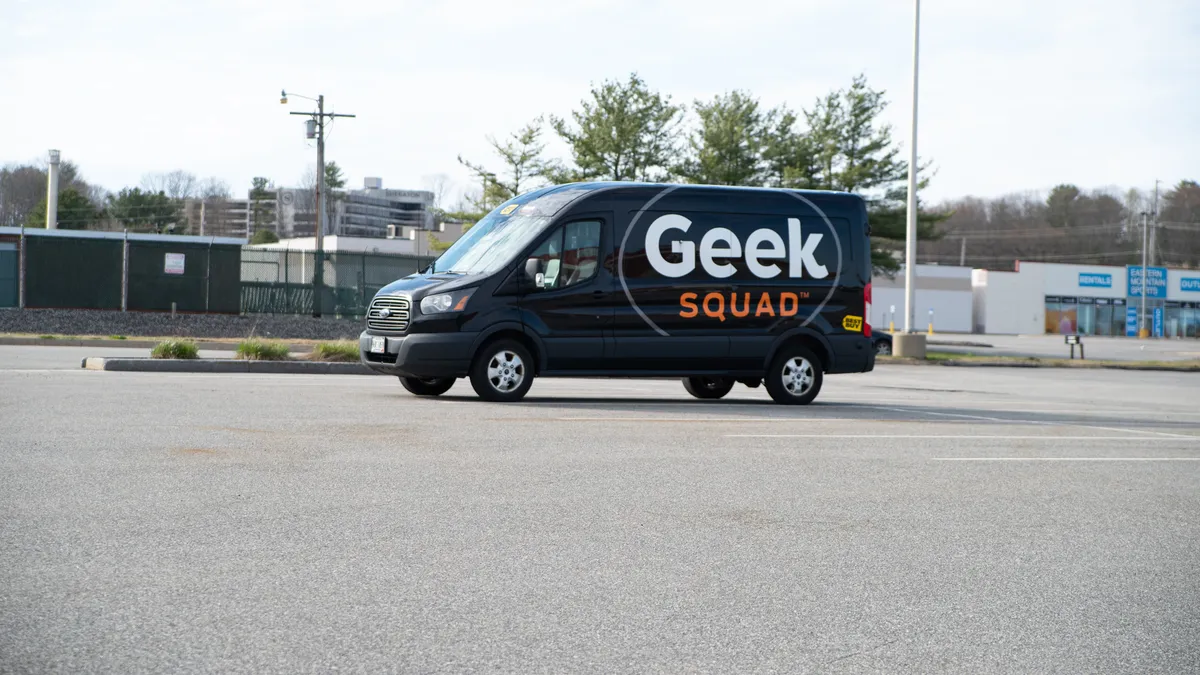 A dark blue van with the word "Geek" in large white letters is parked in a lot.