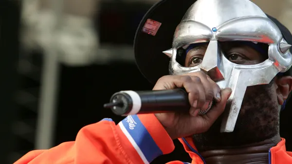 MF Doom stands on stage holding a microphone.