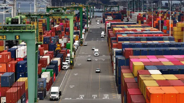 Trucks drive next to stacked containers at the Port of Oakland on Aug. 1, 2025, in Oakland, California.