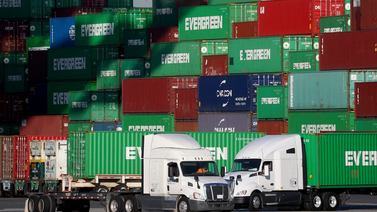 Trucks driving past a stack of shipping containers at the Port of Los Angeles