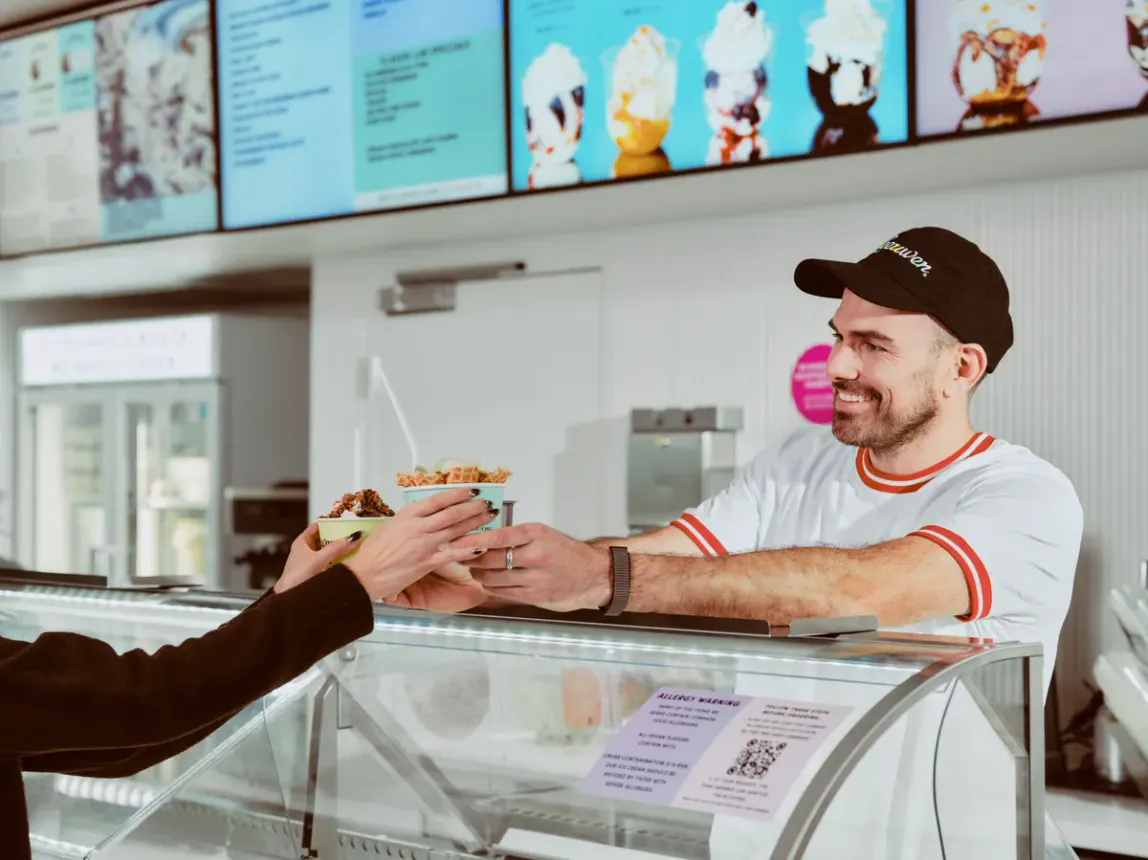 Ice cream shop owner handing out ice cream.
