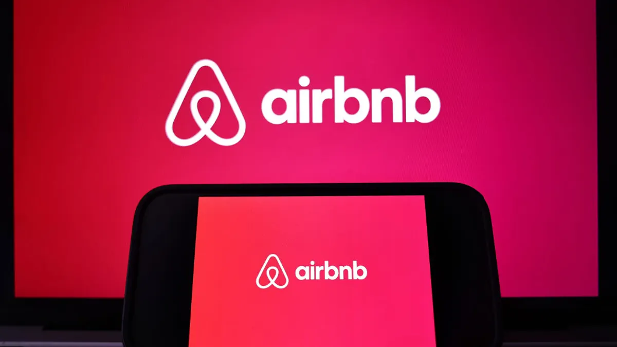 The Airbnb logo is displayed on a computer monitor and cell phone.
