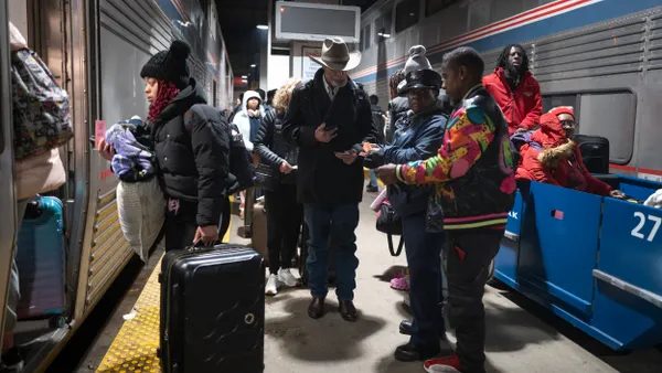Many people in winter coats on a train platform boarding a train.