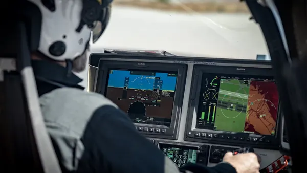 Pilot wearing a helmet looking at digital displays from inside an aircraft.