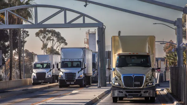 Trucks drive into United States from Mexico at a port of entry,