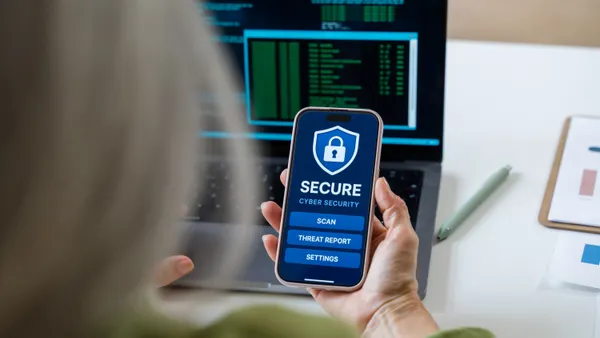 A person holds a smartphone with a secure padlock icon and a cyber security app on the screen.