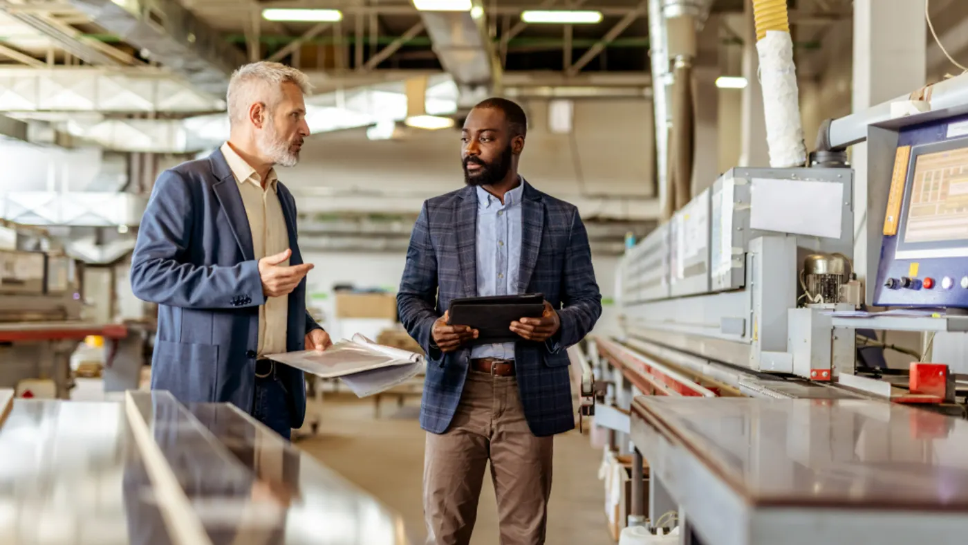 Two professionals interact in a manufacturing facility.