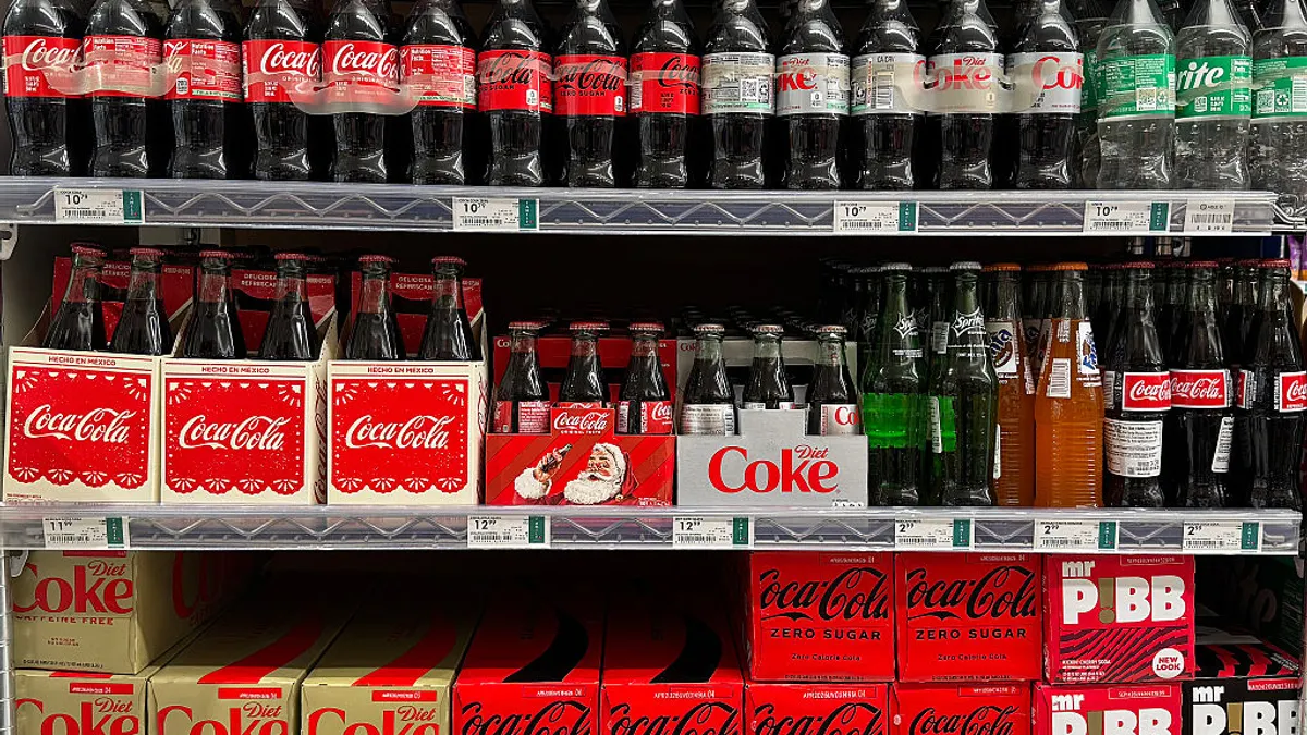 bottles of Coca-Cola are displayed on a store shelf