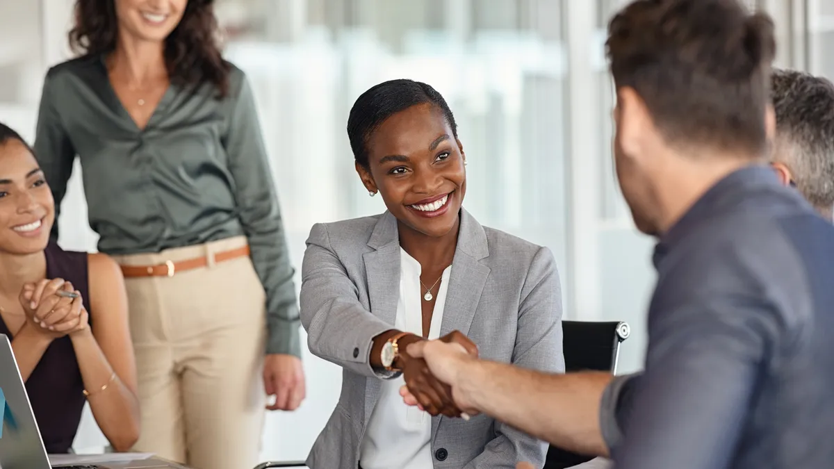 Businesswoman and businessman shaking hands at meeting.