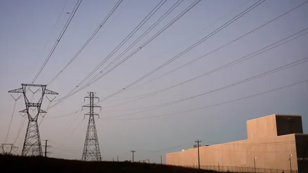 A gray white and data center seen next to power lines against a twilight sky.