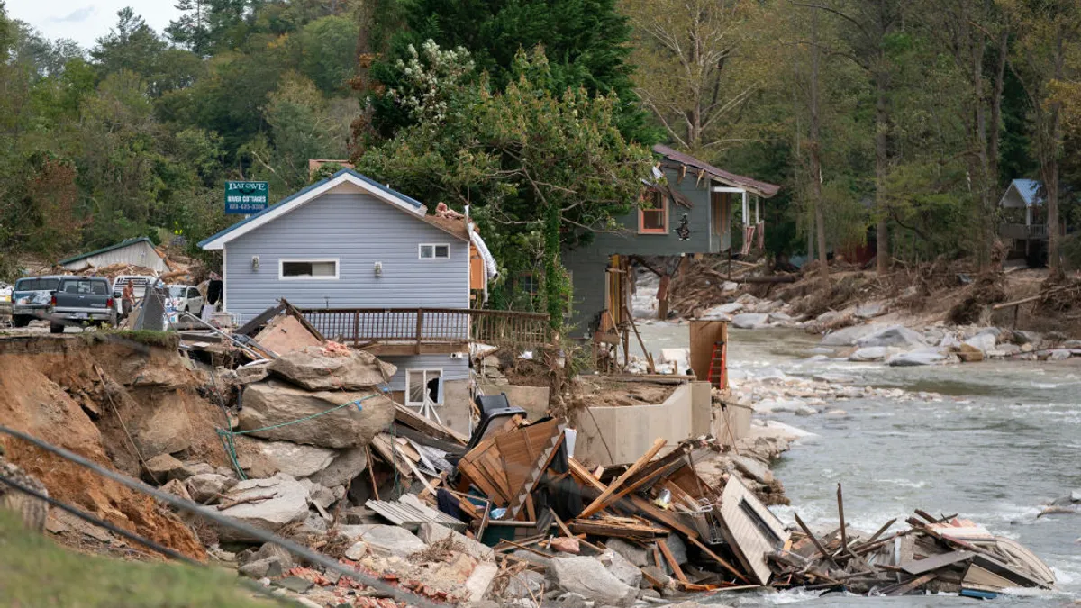 Building debris falling into a river. Other houses still stand by the river.