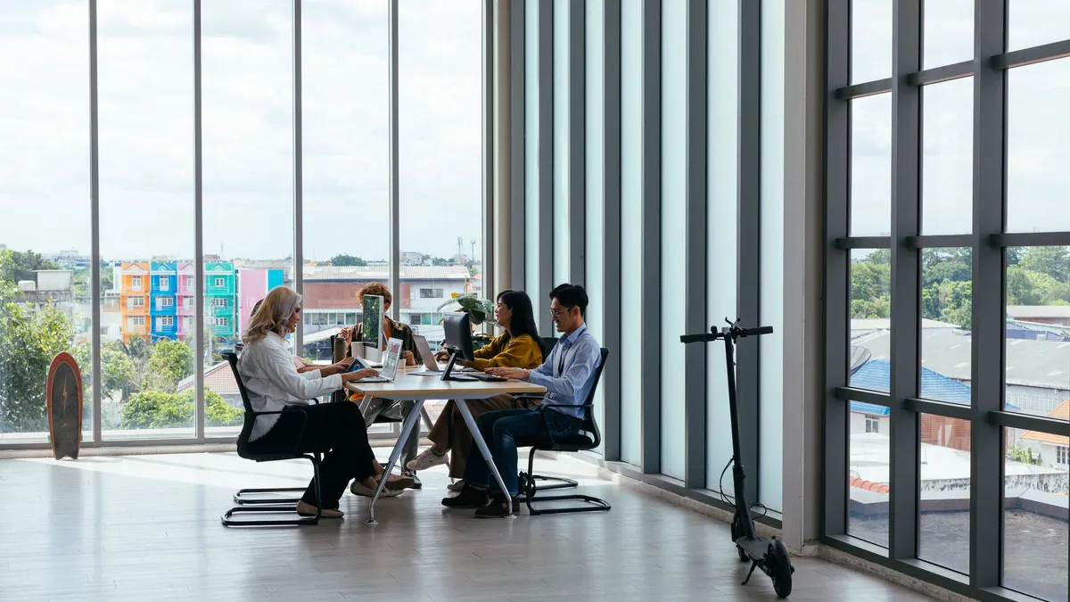 Cowokers in a modern office with tall windows.