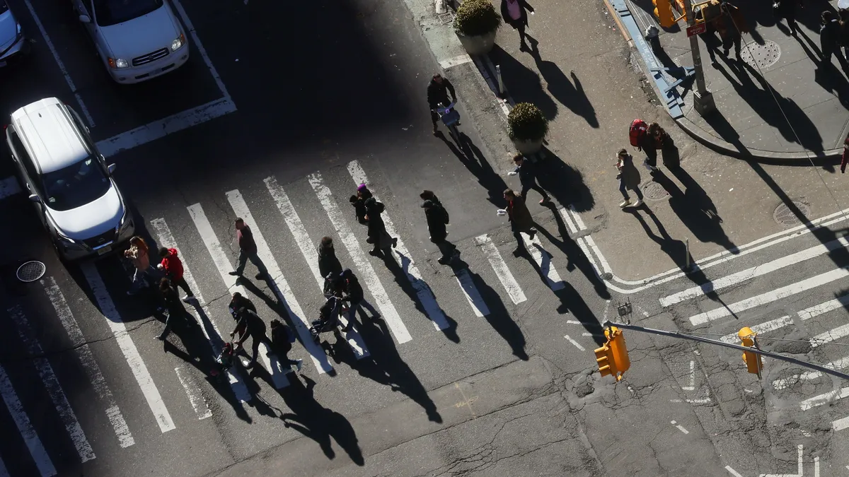 Overhead view of pedestrians crossing a street in midtown Manhattan.