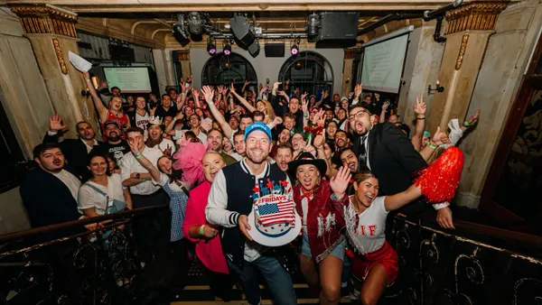 An image of a group of people with a person in the front holding a cake with an American flag on it wiht the words TGI Fridays