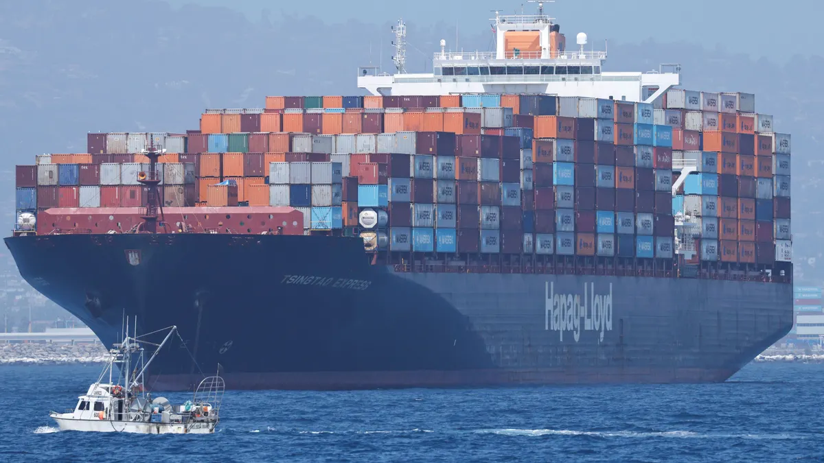 A small fishing boat passes a large container ship near the Port of Los Angeles
