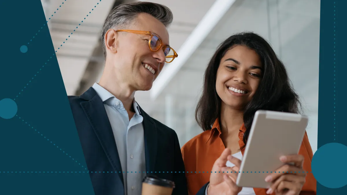 Two colleagues smiling and looking at a tablet