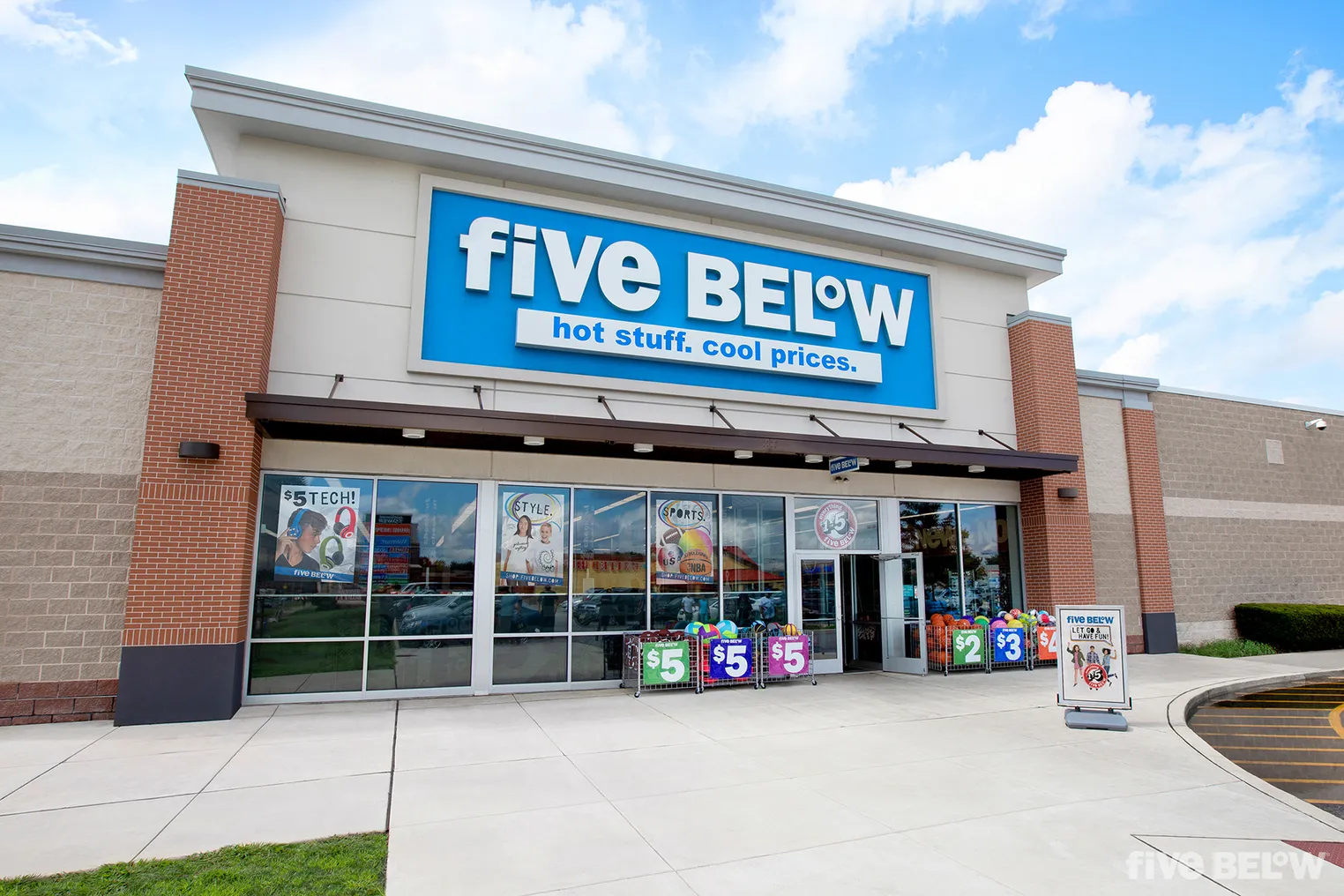 The exterior of a Five Below store during the daytime with a blue sky