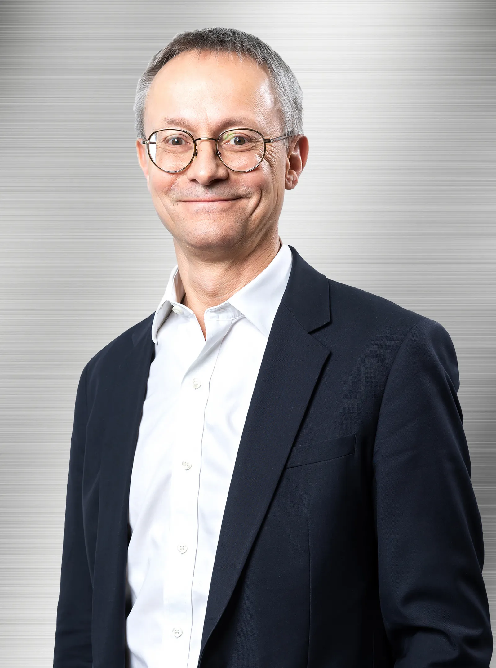 A man with glasses poses for headshot.